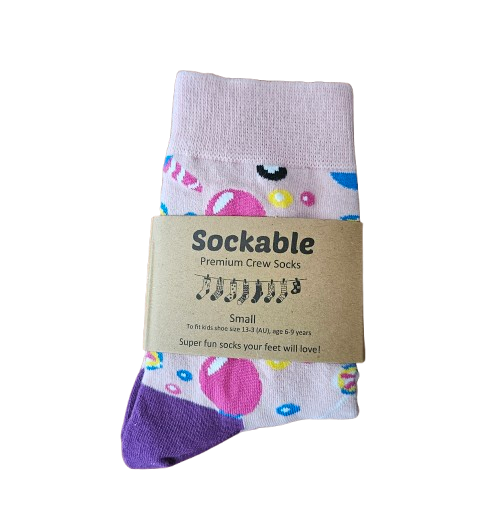 A pair of children's crew socks by Sockable, featuring a pastel pink and white base with colorful bubble patterns and a purple toe, with label.