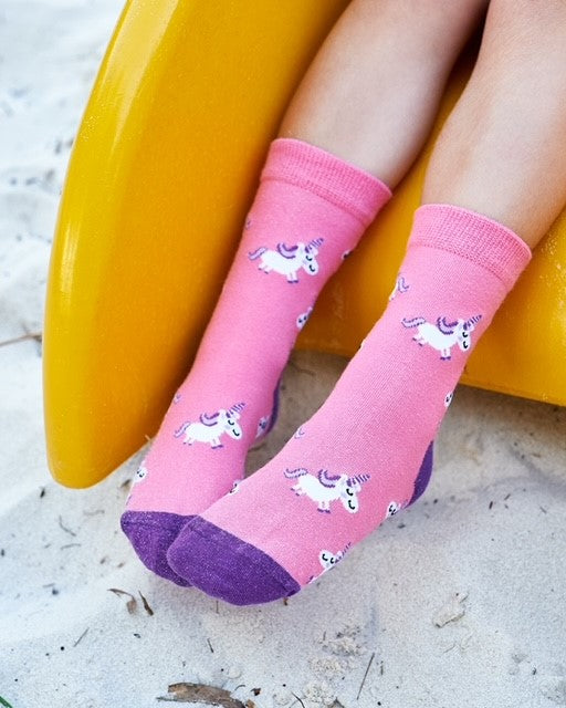 Pink unicorn socks worn by a child at the playground