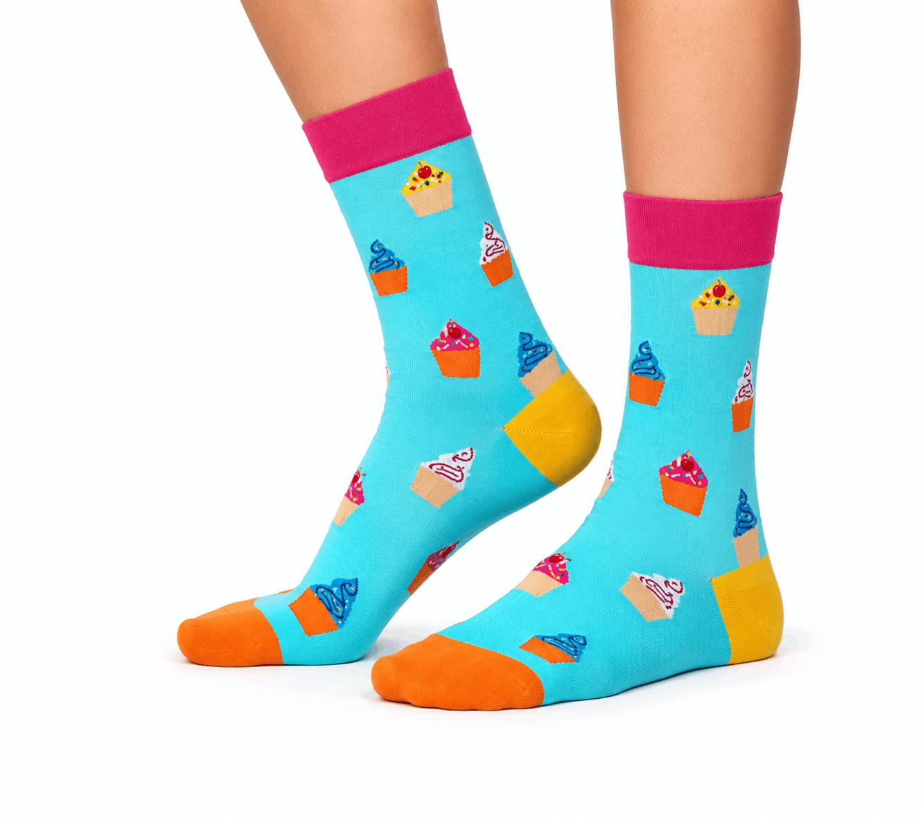 A pair of bright turquoise crew socks with a colorful cupcake print, pink cuffs, and orange and yellow toes, shown on a person's feet against a white background.