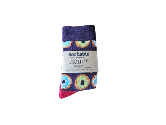 A pair of Sockable branded crew socks with a purple base and colorful donut patterns, labeled.
