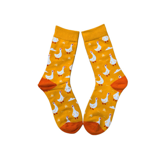 Yellow socks with white geese on them laid flat, with orange heel and toe.